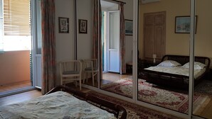 Een slaapkamer met een grote spiegel, een bed, een stoel en uitzicht op een balkon.