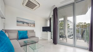 A modern living room with a sofa, glass coffee table, and a flat-screen TV. - Apartamenty Sun & Snow Dune B (Mielno)