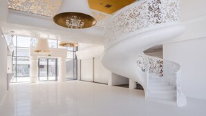 A spacious, modern lobby with a white spiral staircase and large chandeliers. - Apartamenty Sun & Snow Dune B (Mielno)