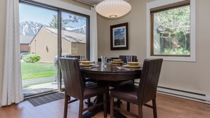 Un coin repas avec une table ronde, quatre chaises, un luminaire suspendu et un tableau encadré au mur.