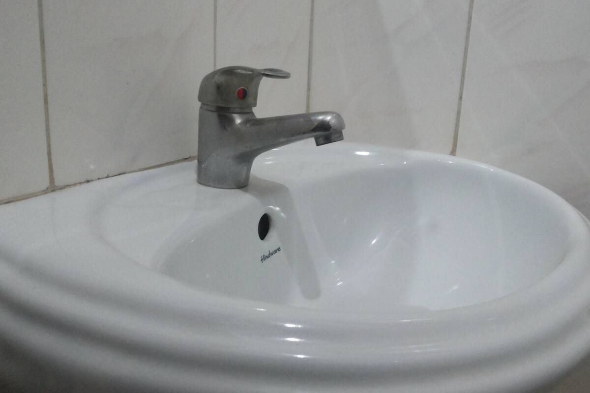 A white ceramic sink with a single faucet and a drain hole.