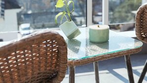 A glass-top table with a potted plant and a candle, surrounded by wicker chairs, overlooking a cityscape. - Floral Hotel Hangzhou Puyushanyu (Hangzhou)