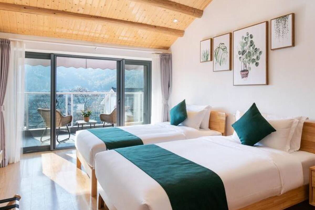 Habitación de hotel con dos camas, un balcón con vistas y techo de madera.