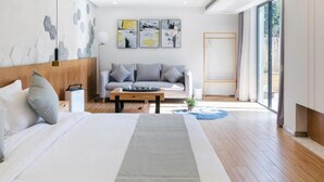 A modern hotel room with a large bed, a sofa, a coffee table, and artwork on the walls. - Floral Hotel Hangzhou Puyushanyu (Hangzhou)