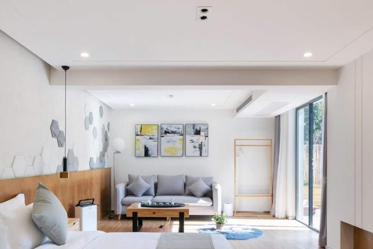 Una habitación de hotel moderna con una cama grande, un sofá, una mesita de café y obras de arte en las paredes.
