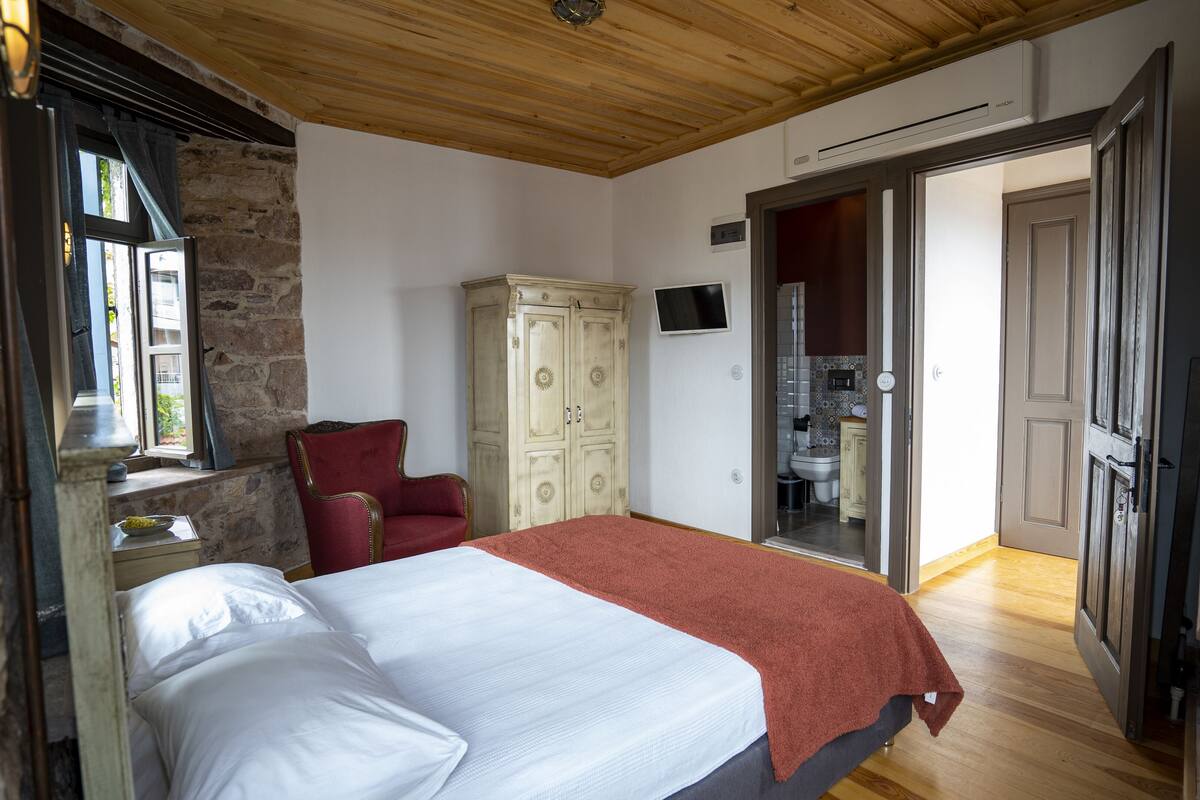 A bedroom with a bed, a wardrobe, a chair, and a TV.
