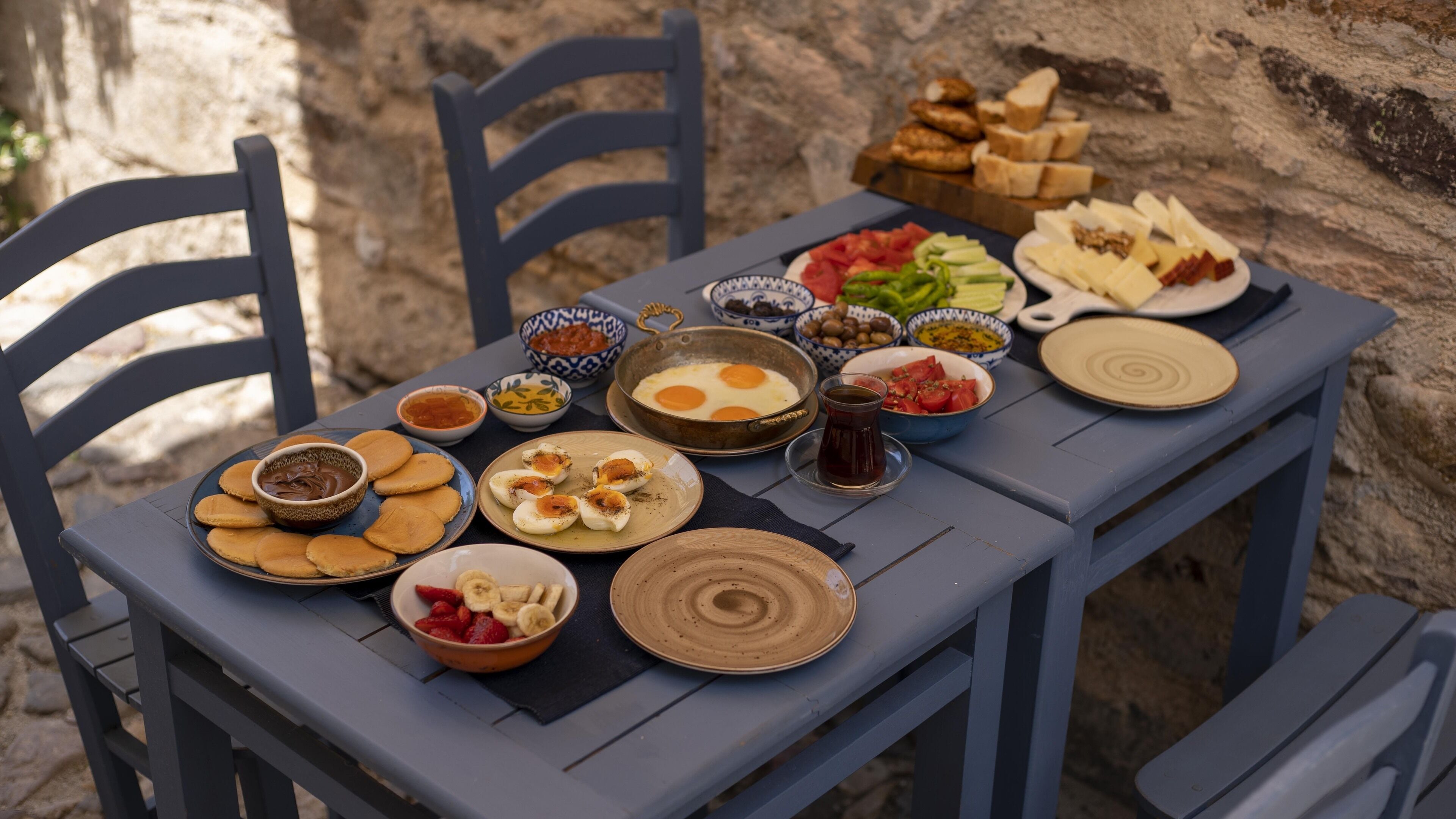 A table set with various dishes including eggs, fruits, and bread, suggesting a meal setting outdoors.
