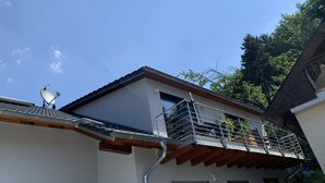 Ein modernes Gebäude mit Balkon, Satellitenschüssel und Holzträgerbauweise.