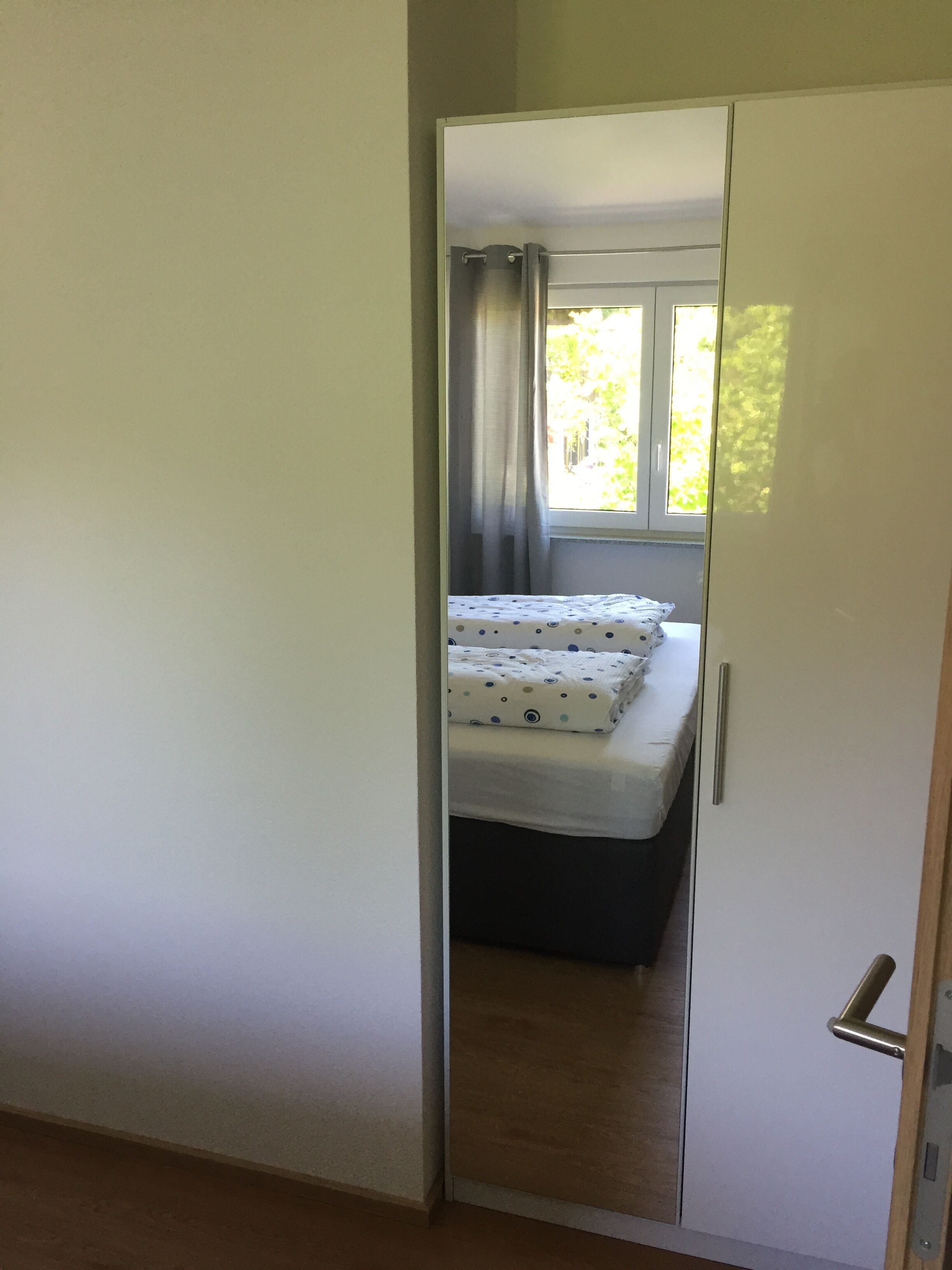 Une chambre à coucher avec un lit, une fenêtre avec des rideaux et une porte.