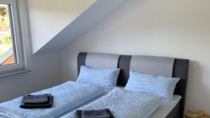 Ein modernes Schlafzimmer mit einem Bett, Kissen und einem kleinen Holzschemel.