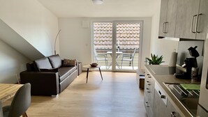 Eine moderne Wohnung mit Wohnbereich, Küchenzeile und einem Balkon mit Blick.