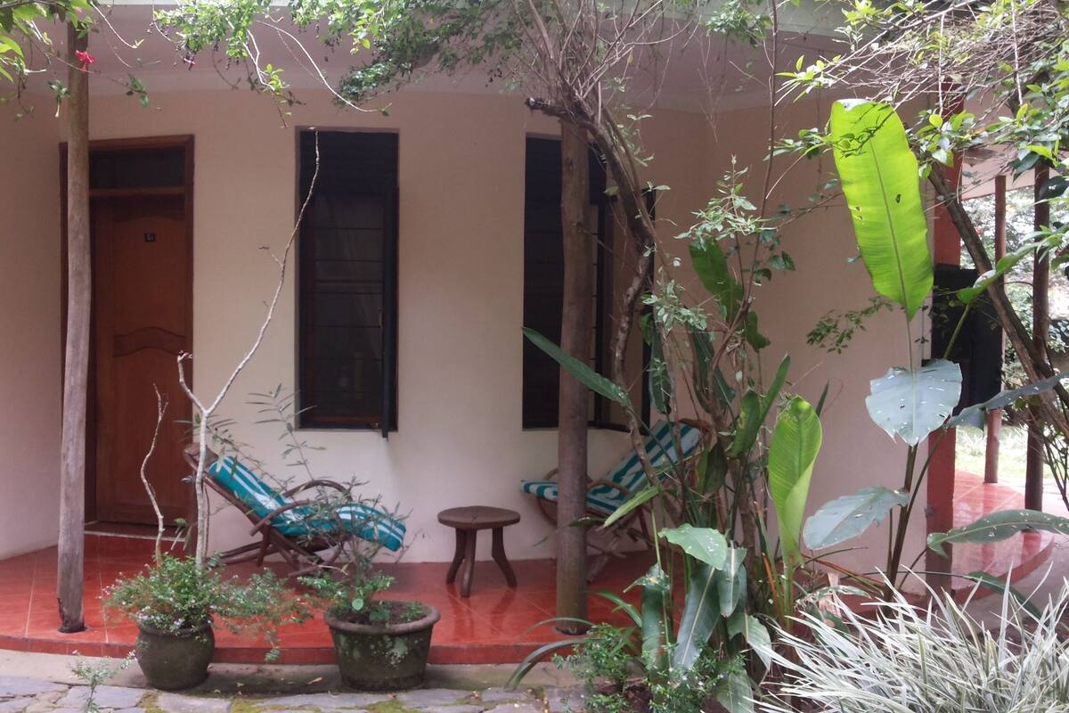 A covered porch with a wooden door, a small table, and two chairs.
