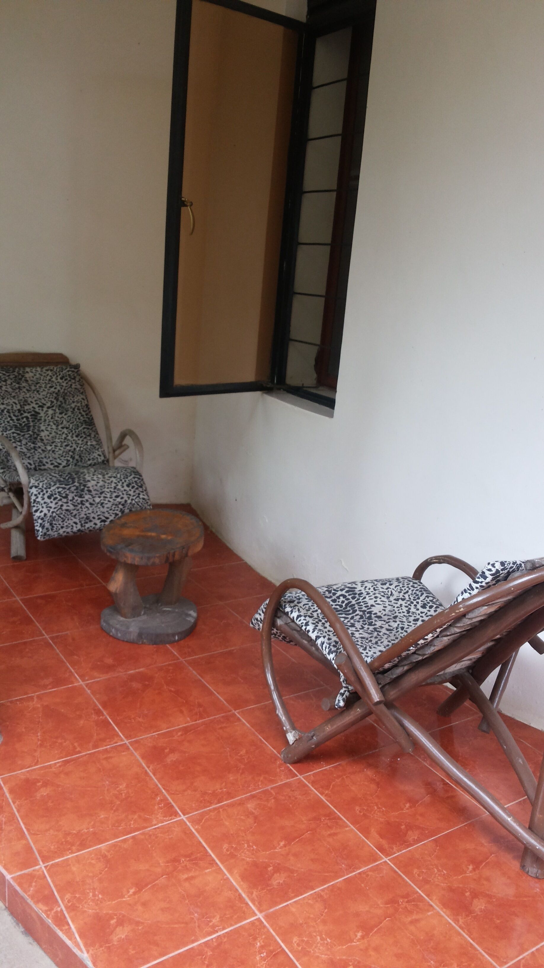 A room with a tiled floor, a wooden rocking chair, a small round table, and a patterned sofa.