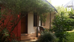 Una casa con porche cubierto, una silla y un pequeño jardín.