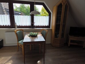 A dining area with a table and chairs, a radiator, a cabinet, and a television. - Upper apartment in Westeraccum with balcony (Westeraccum)
