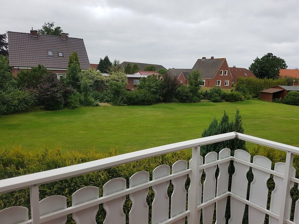 A residential area with houses, a well-maintained lawn, and a white picket fence.