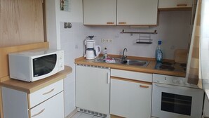 A compact kitchen with a microwave, coffee maker, sink, and a small oven. - Upper apartment in Westeraccum with balcony (Westeraccum)