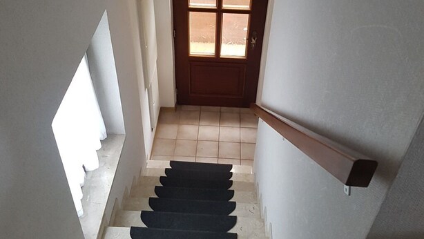A staircase with a handrail, leading to a door with a window. - Upper apartment in Westeraccum with balcony (Westeraccum)