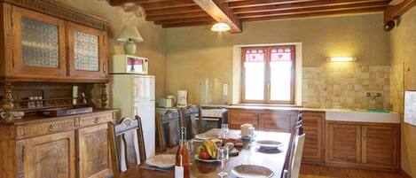 A traditional kitchen with wooden cabinets, a large dining table, and a built-in oven.