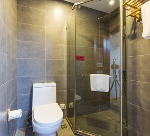 Ein modernes Badezimmer mit einer Duschkabine, einer weißen Toilette und einem Handtuchhalter.