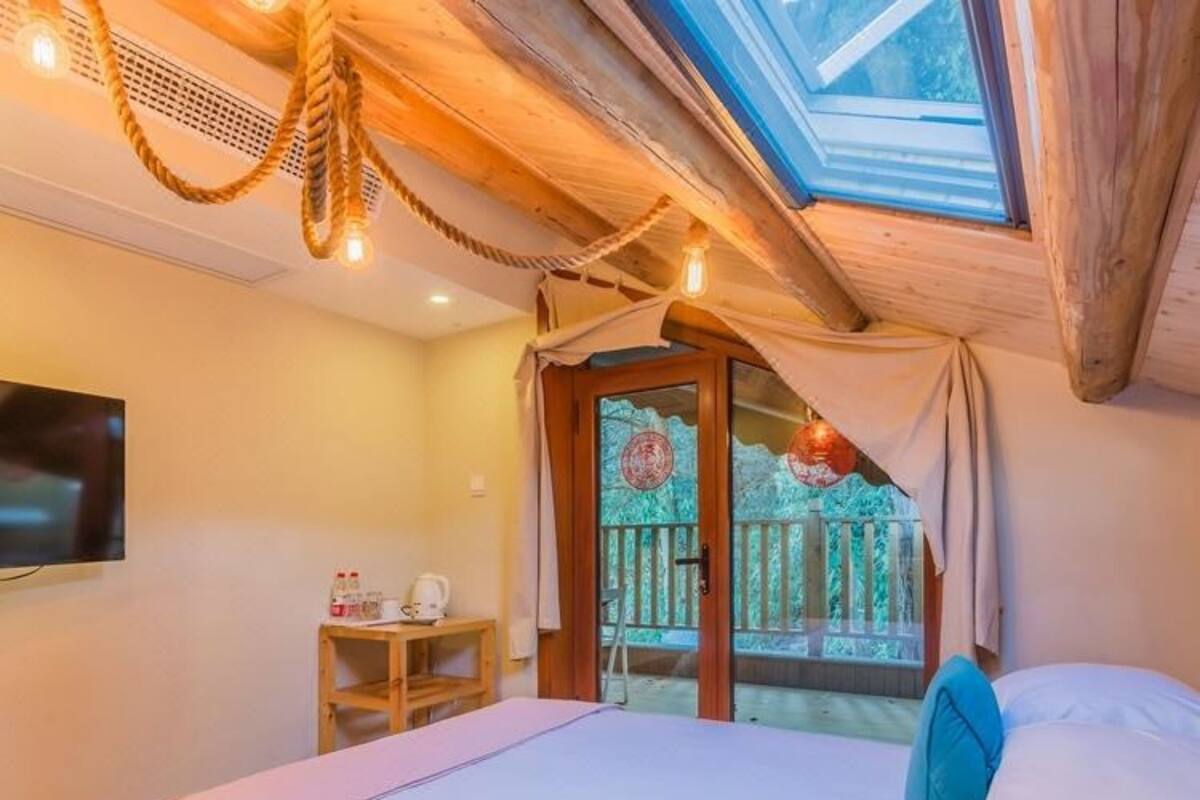 Un dormitorio con una cama grande, un televisor, una mesita con una tetera y vistas a una terraza de madera.