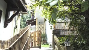 Una estrecha escalera de madera que lleva a una casa tradicional, con cerca de bambú y puerta de madera.