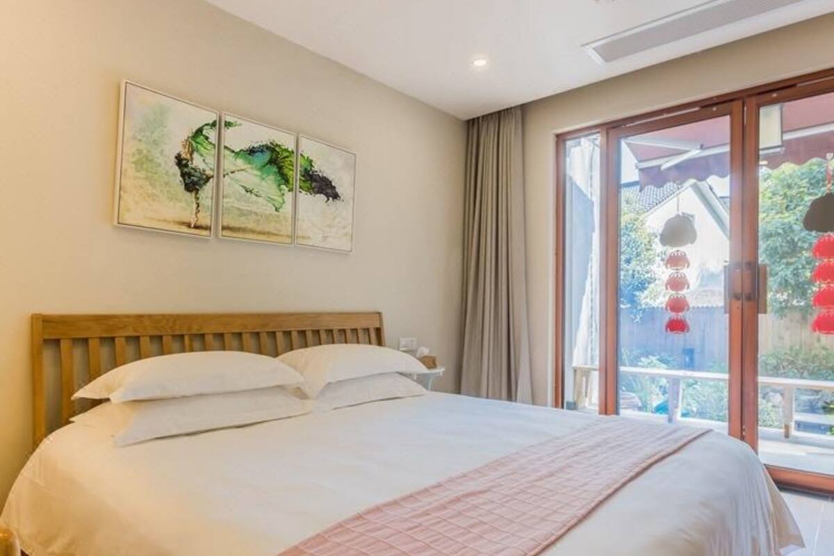 Un dormitorio con una cama grande, una mesita de noche y una ventana con cortinas.