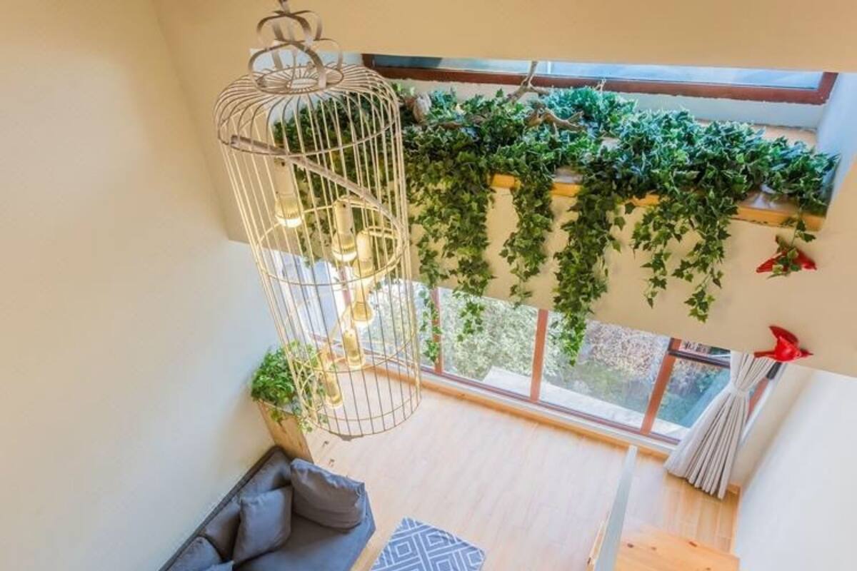 Un interior moderno con una escalera de madera, un sofá gris y una lámpara colgante.