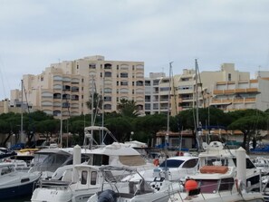 A marina with several boats docked, surrounded by multi-story buildings with balconies.