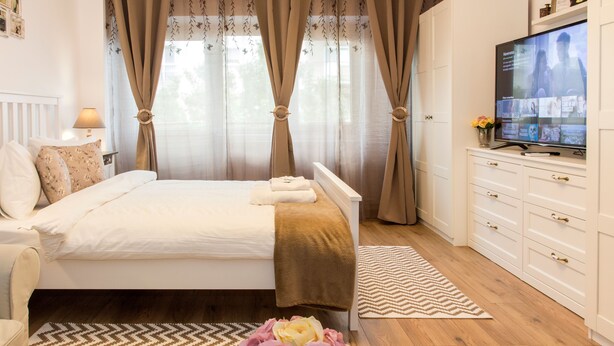 Une chambre à coucher avec un lit, une télévision, une commode et un vase de fleurs.