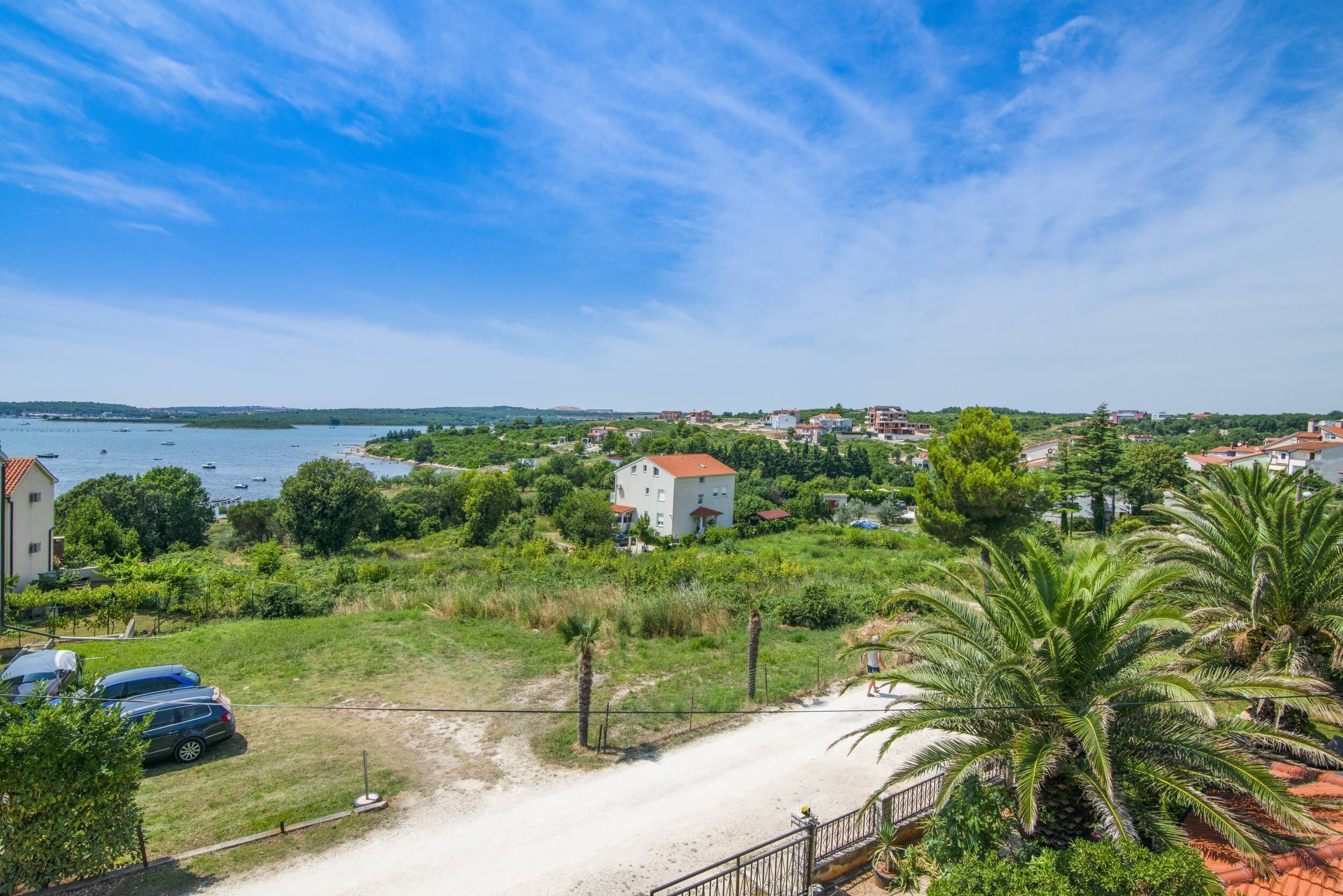 Une vue sur la côte, avec un bâtiment blanc, un sentier sablonneux et une voiture garée.