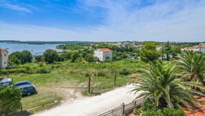 A coastal view with a white building, a sandy path, and a parked car. - Apartments Tara Apt 2 (Medulin)