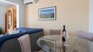 Een moderne woonkamer met een glazen tafel, een bank en een lijst met een landschap.