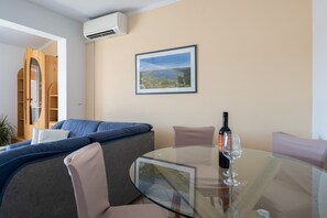 A modern living room with a glass table, a sofa, and a framed landscape painting. - Apartments Tara Apt 2 (Medulin)