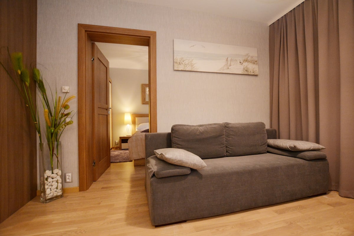 Una sala de estar moderna con un sofá gris, un jarrón con flores y un cuadro en la pared.