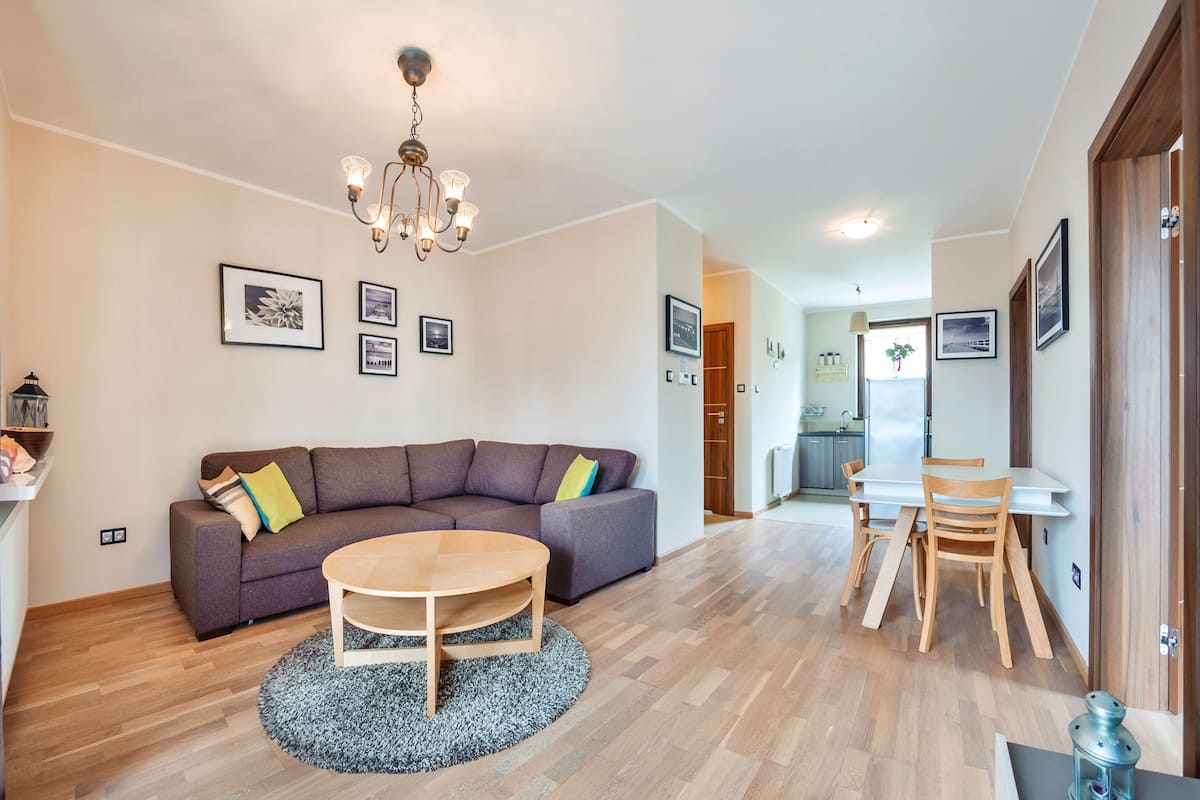 Una sala moderna con un sofá modular, una mesa de centro redonda y un comedor con mesa y sillas.