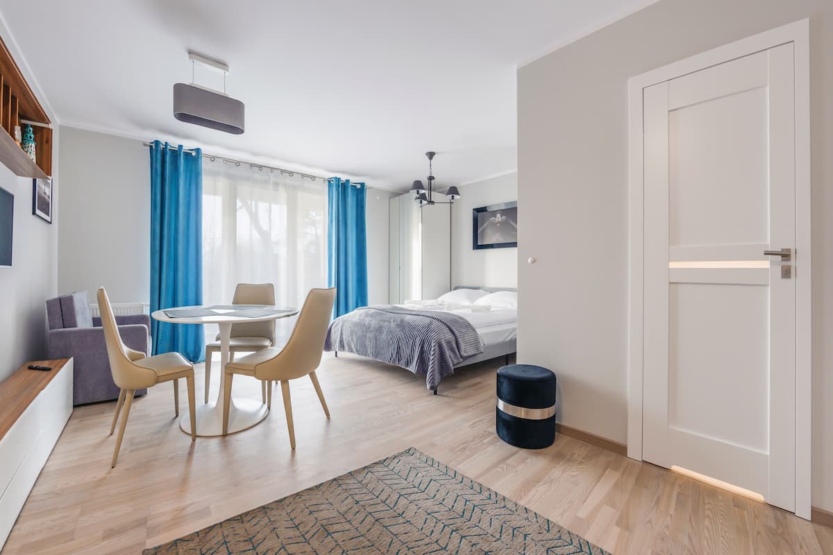 Un dormitorio moderno con cama, mesita de noche y ventana con cortinas.