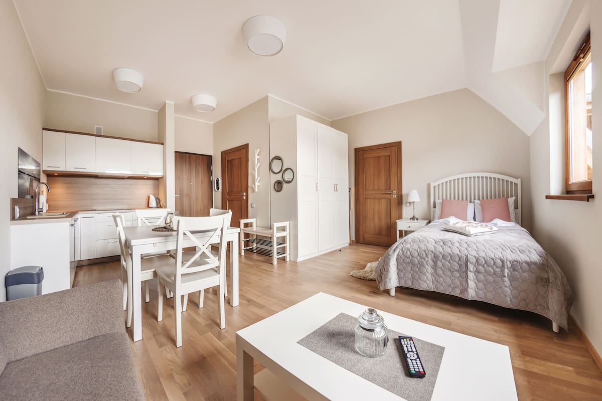 Un espacio habitable compacto con kitchenette, comedor y un dormitorio con cama y mesita de noche.