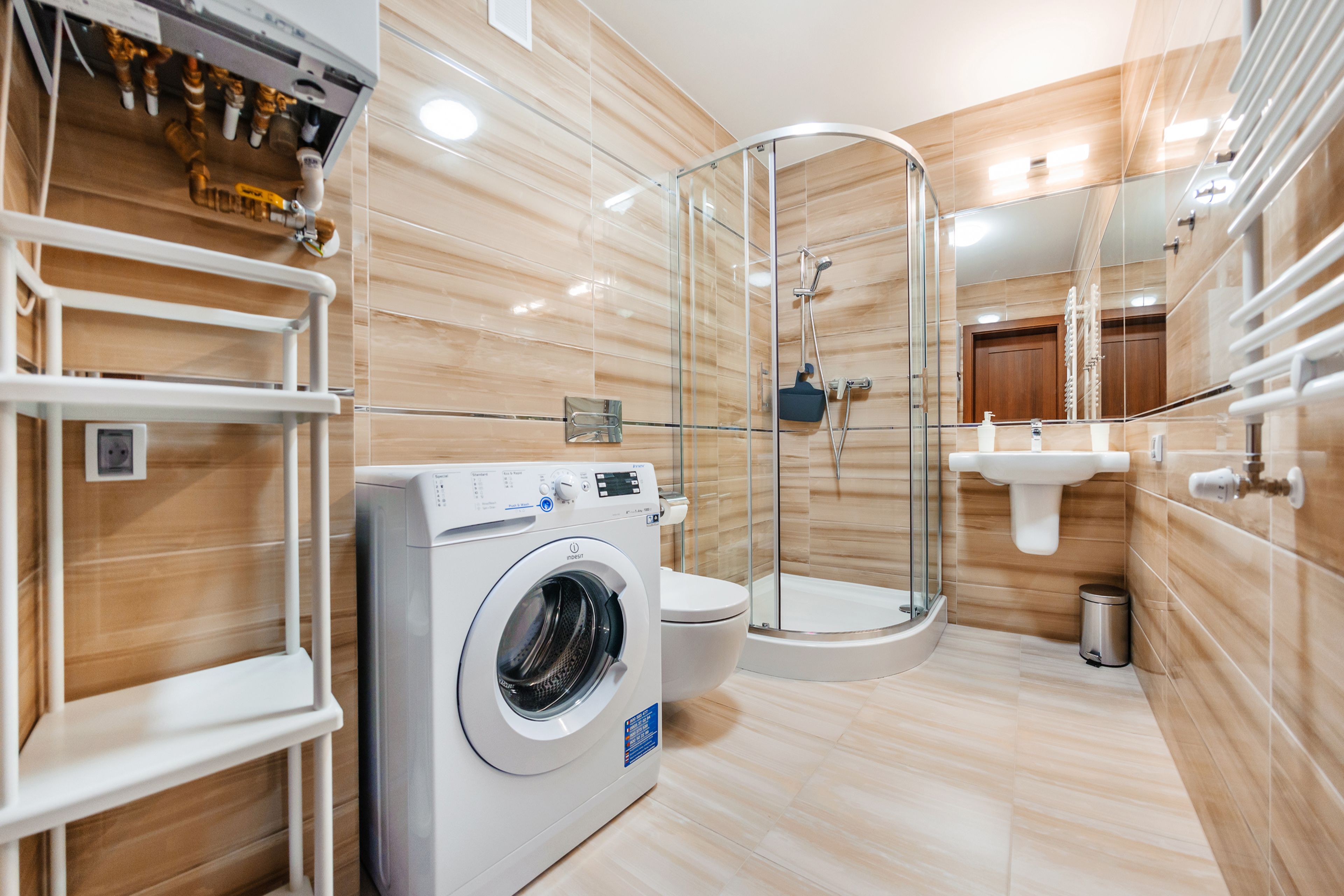 Un baño moderno con lavadora, inodoro, cabina de ducha de vidrio y lavamanos.