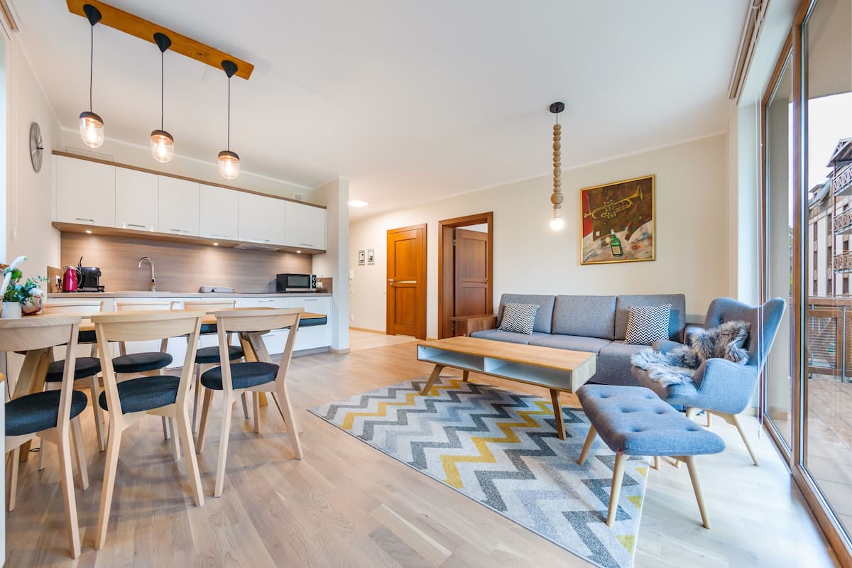 Una cocina moderna con armarios de madera, una mesa de comedor con sillas e iluminación colgante.