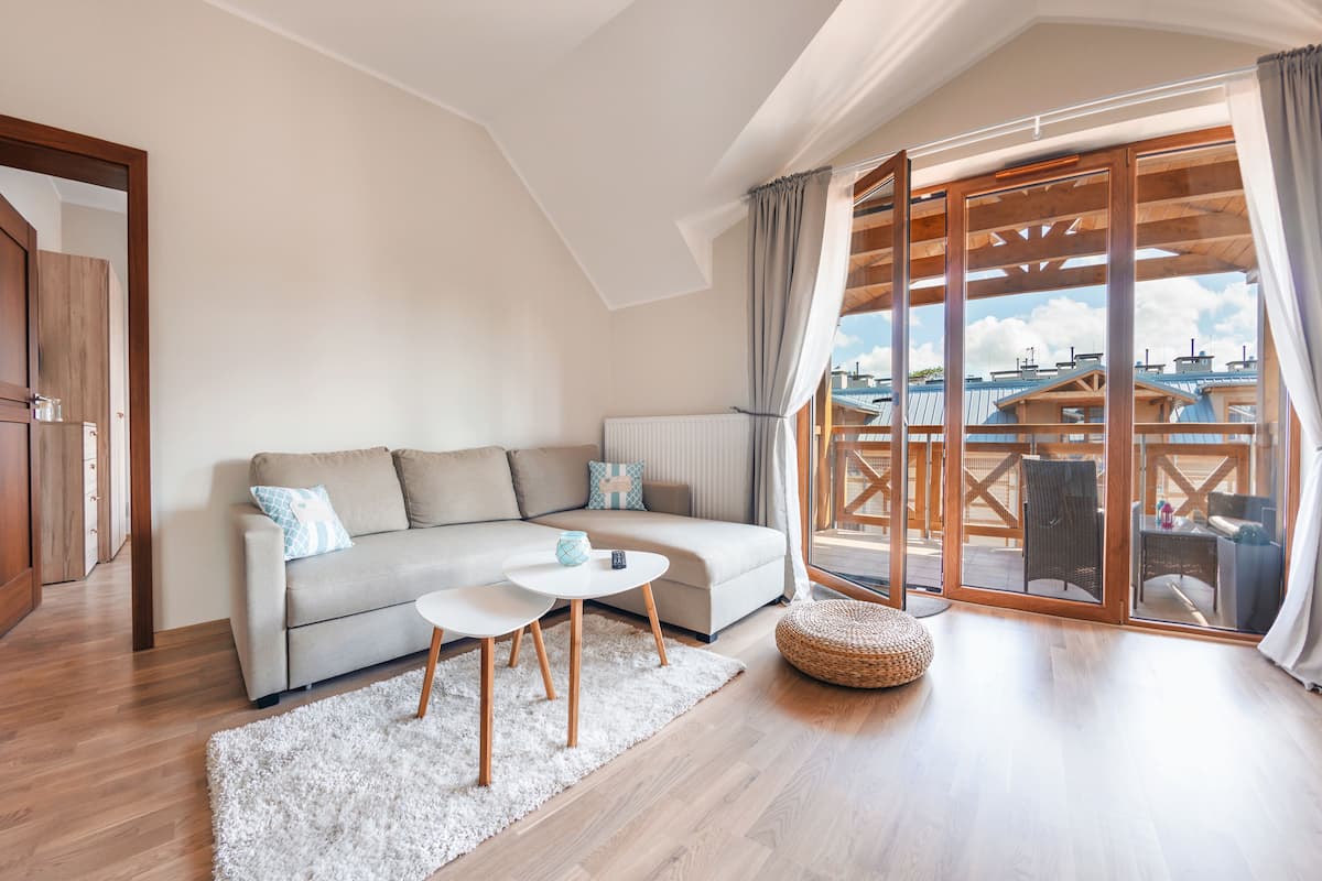 Una sala de estar moderna con un sofá, una mesa de centro y vistas de la ciudad a través de amplios ventanales.