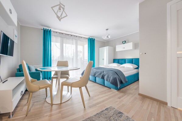 Une chambre moderne avec un lit, un bureau et un coin repas.