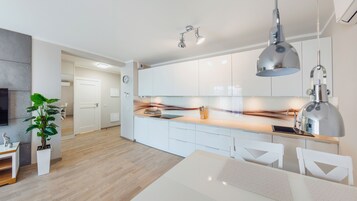 A modern kitchen with white cabinets, a wooden countertop, and a dining area with a white table and chairs.