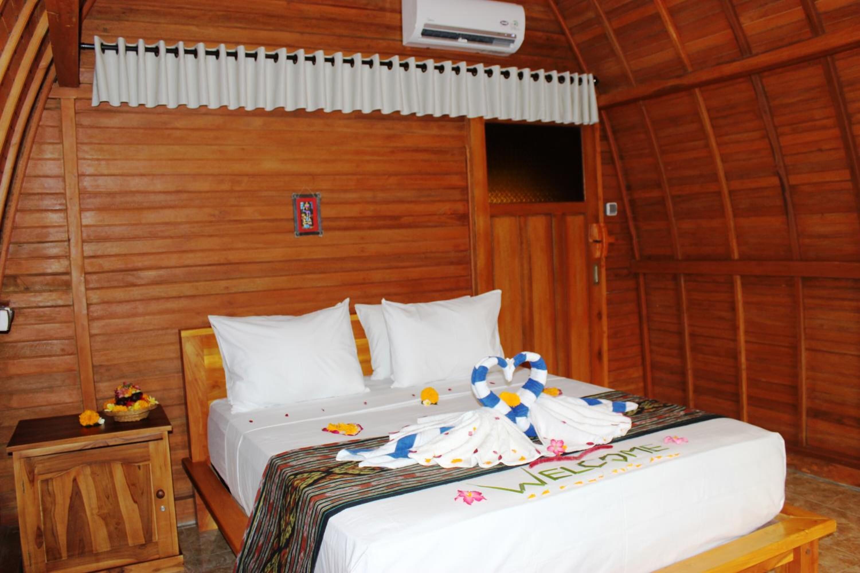 Un dormitorio de cabaña de madera con una cama, una mesita de noche y una ventana.