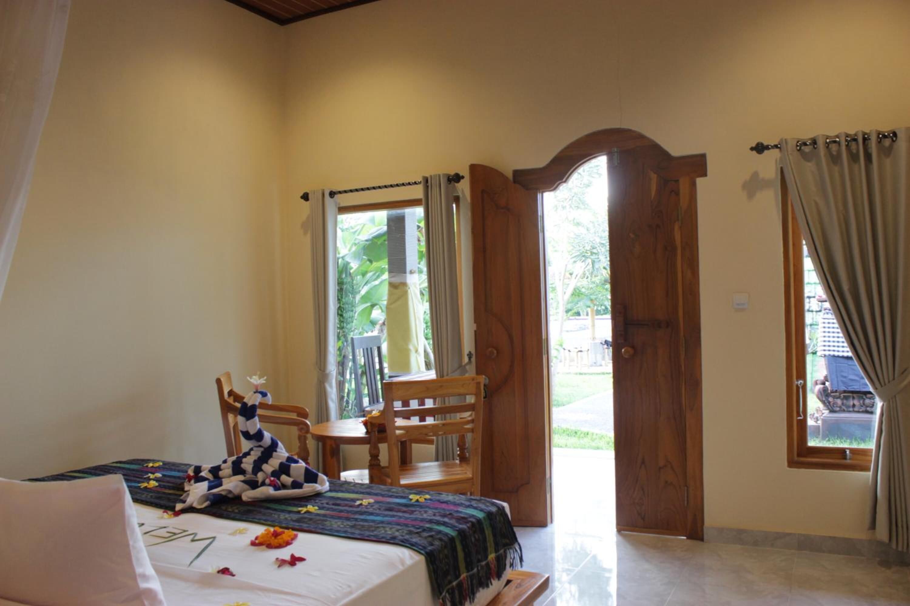 Una habitación con cama, una silla, una mesa y un ventanal con cortinas.