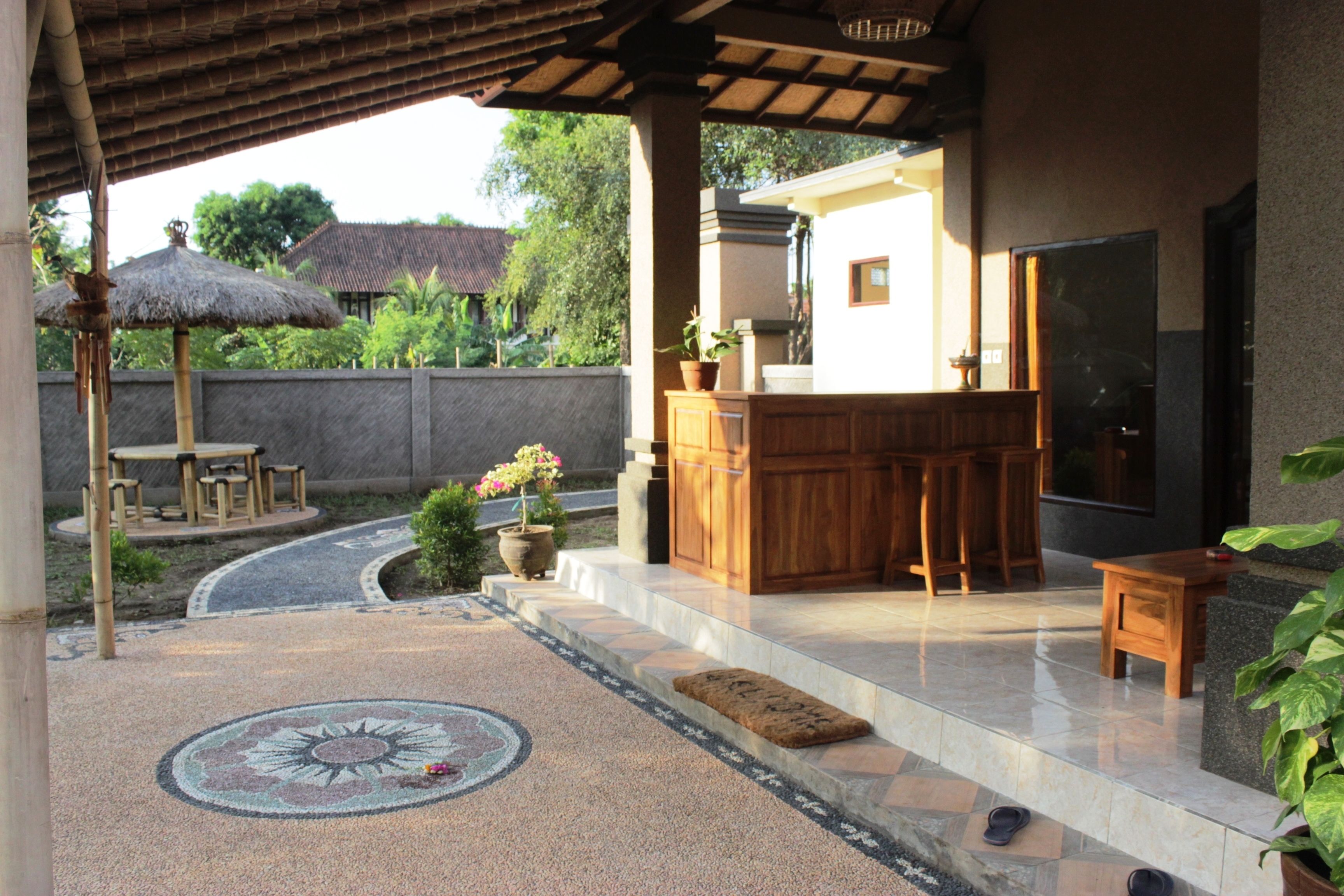 A covered outdoor area with a bar, seating, and a decorative rug.