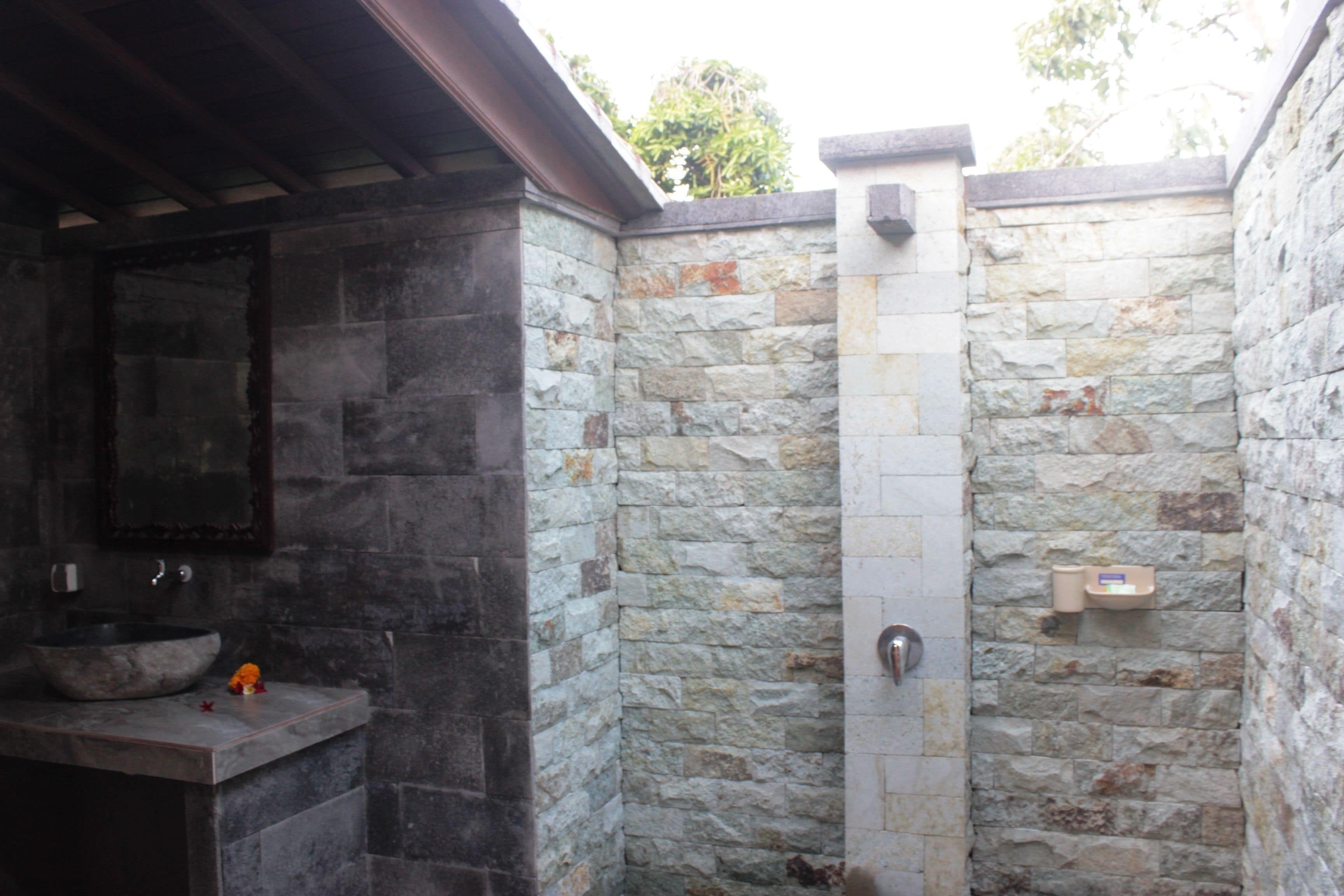 A stone-walled bathroom with a built-in sink and shower.
