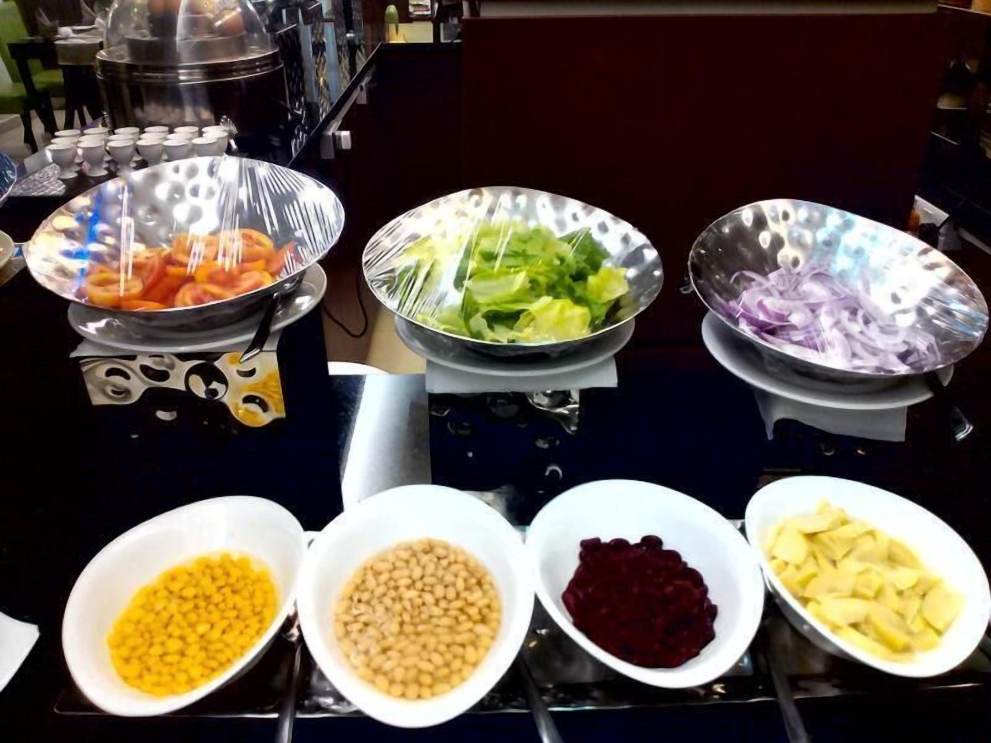 A buffet table with various food items including vegetables, beans, and potatoes.