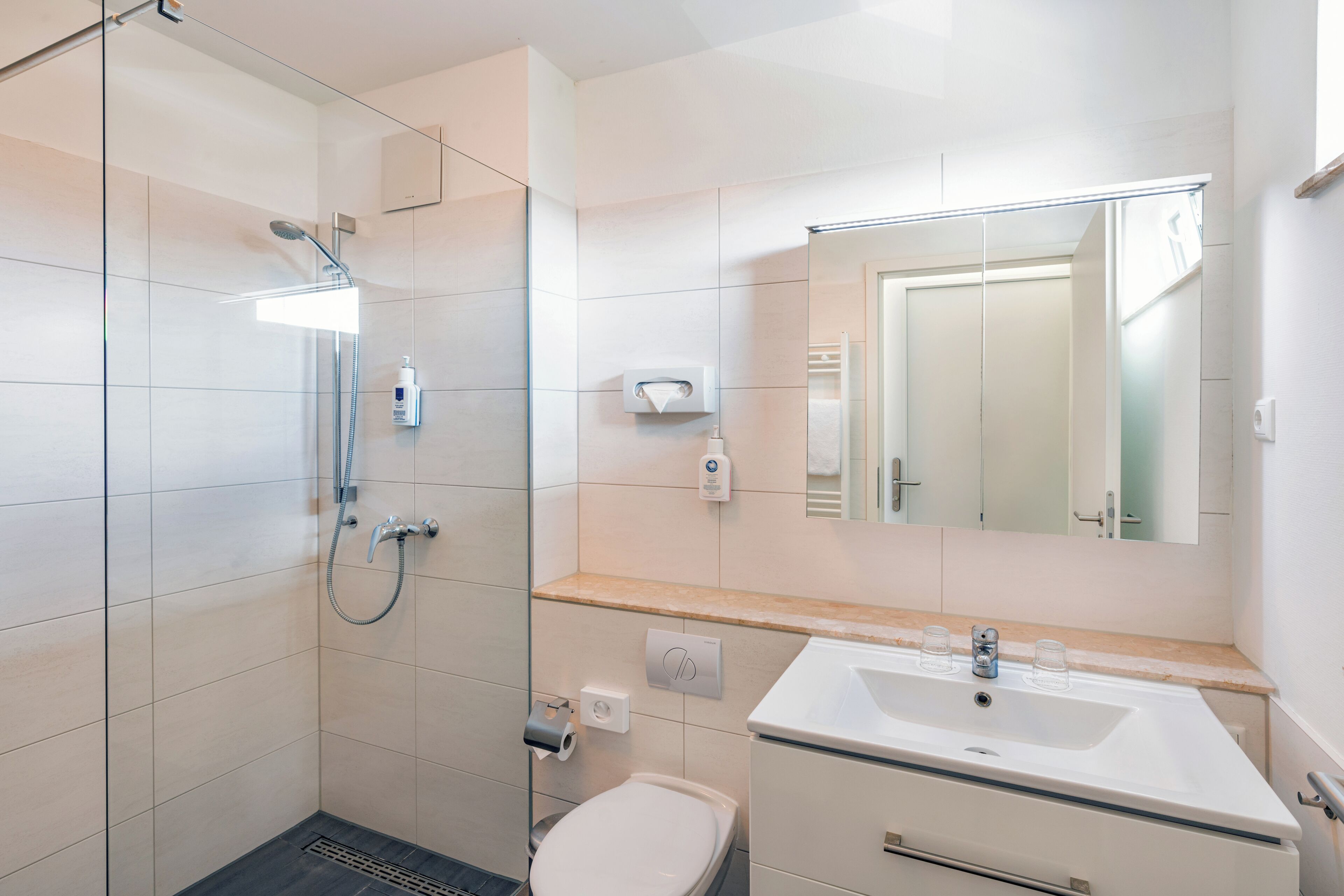 A modern bathroom with a glass-enclosed shower, a white sink, and a mirror above the sink.