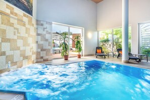 An indoor swimming pool with clear water, surrounded by tiled walls and potted plants. - SEETELHOTEL Nautic Usedom Hotel & Spa (Koserow)